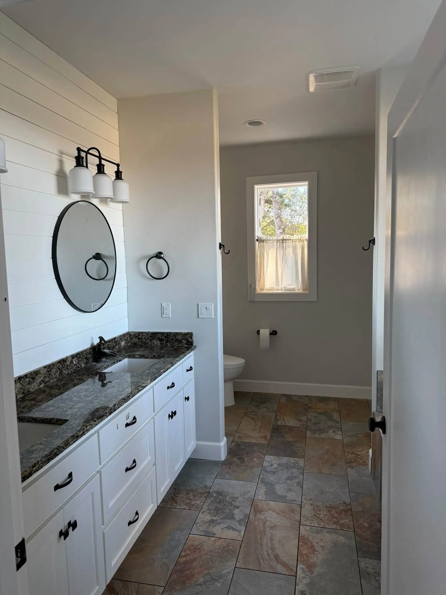Finished bathroom with white shiplap, white vanity and soft gray walls