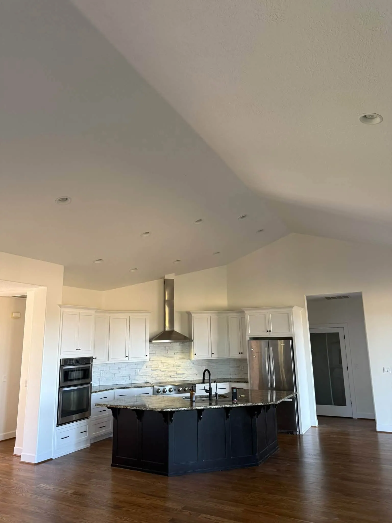 Finished kitchen with a vaulted ceiling, white cabinets and a dark island